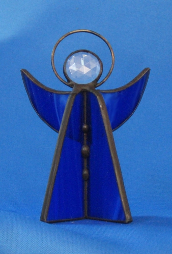 Standing angel,stained glass,dark blue,opalescent,with faceted glass stone,clear,height ca. 9,5 cm,item number 30039B,manufactured in our own atelier.Carmen Harusta,Glasinsel ®,Goettingen,Germeny (front view).